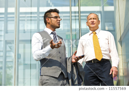 Senior businessman and young businessman outside glass building 11557569