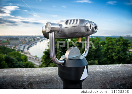 Binocular next to the waterside promenade i looking out to the city and river 11558268