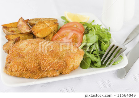 Wiener Schnitzel - Breaded fried veal, potato wedges and salad. Wiener Schnitzel - Breaded fried veal, potato wedges and salad. 11564049