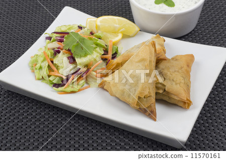 Samosas served with mint raita salad and lemon slices  11570161