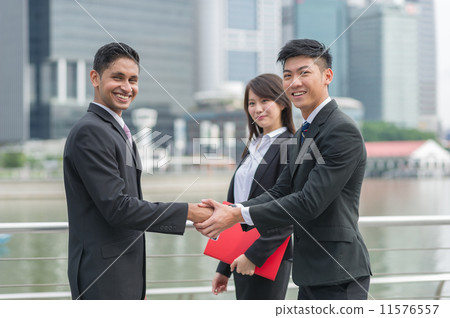 A successful Chinese businessman with his female assistant hand shake with his Indian partner 11576557