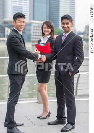 A partnership deal has been sealed with a warm handshake between two partners with a female witness A partnership deal has been sealed with a warm handshake between two partners with a female witness 11576566