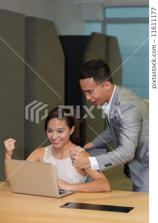 Two overjoyed young asian co-workers celebrate after received good news through an email in office Two overjoyed young asian co-workers celebrate after received good news through an email in office 11611177