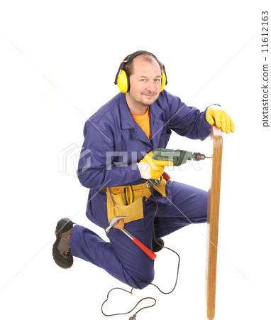 Worker in ear muffs with drill and board. 11612163