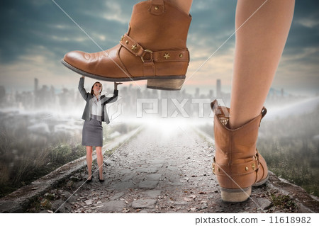 Composite image of cowboy boots stepping on businesswoman 11618982