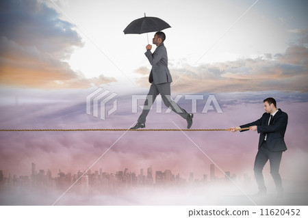 Young businessman pulling a tightrope for business man Young businessman pulling a tightrope for business man 11620452