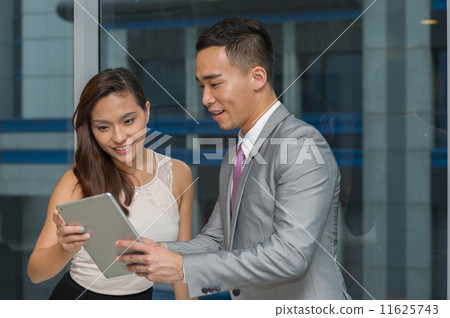 Two young and dynamic asian co-workers are having a discussion or sharing information on the tablet 11625743