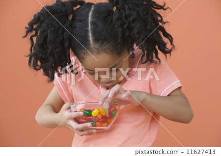 Asian girl with ponytails looking in bowl of candy 11627413