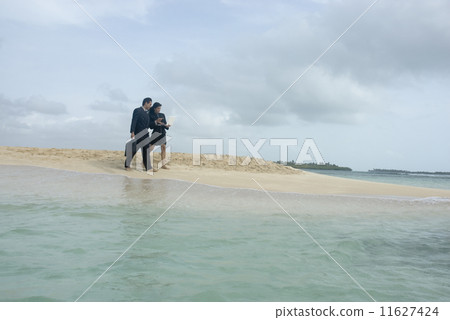 Hispanic businesspeople walking on beach 11627424