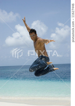 Hispanic man jumping at beach Hispanic man jumping at beach 11627446