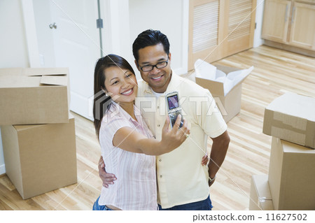 Asian couple taking own photograph in new house Asian couple taking own photograph in new house 11627502