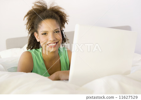 African woman with laptop on bed 11627529