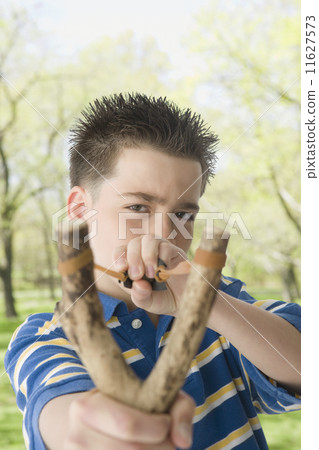 Hispanic boy pulling on sling shot 11627573