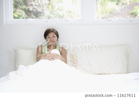 Asian woman sitting in bed 11627611