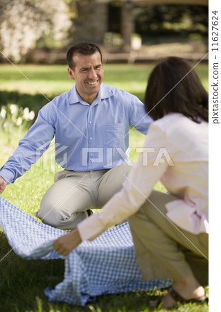 Hispanic couple laying down picnic blanket 11627624