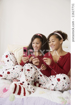 African twin sisters looking at cell phones African twin sisters looking at cell phones 11627731
