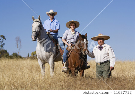 Hispanic man leading couple on horses Hispanic man leading couple on horses 11627732