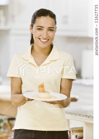 Hispanic woman holding plate of dessert 11627735