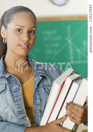 Female Dominican teenager holding her books in classroom 11627842
