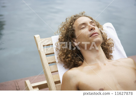 Man in lounge chair next to water Man in lounge chair next to water 11627878