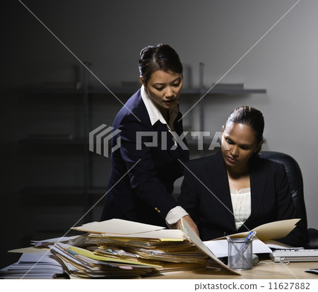 Multi-ethnic businesswomen discussing paperwork Multi-ethnic businesswomen discussing paperwork 11627882