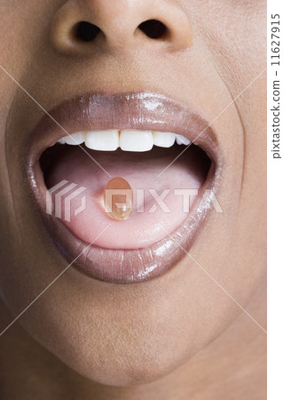 African American woman with vitamin in mouth 11627915