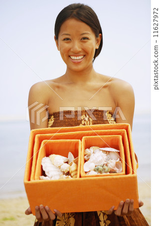 Asian woman holding box of seashells 11627972