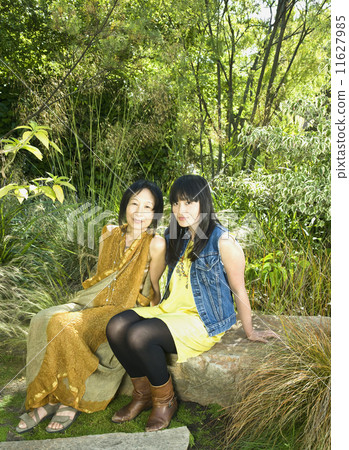 Asian mother and adult daughter sitting in park Asian mother and adult daughter sitting in park 11627985
