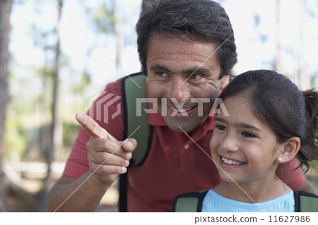 Hispanic father pointing for daughter in woods 11627986