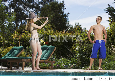 Hispanic woman taking photograph of boyfriend 11628012