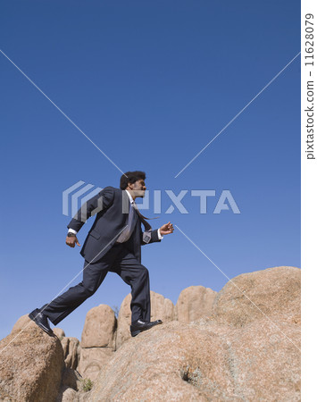 African businessman walking across rocks 11628079