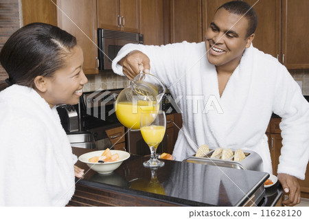 African man pouring orange juice for wife 11628120