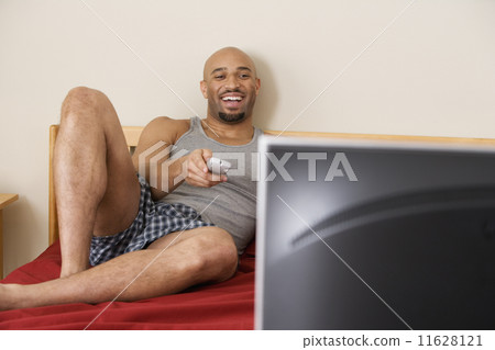 African man watching television in bed 11628121