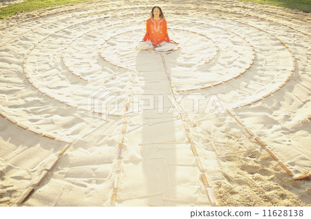 Woman sitting cross-legged in the middle of a meditation labyrinth Woman sitting cross-legged in the middle of a meditation labyrinth 11628138