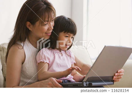 Asian mother and daughter looking at laptop 11628154