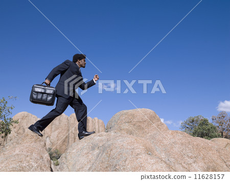 African businessman walking across rocks 11628157