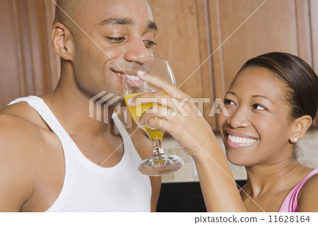 African woman holding juice glass for husband 11628164