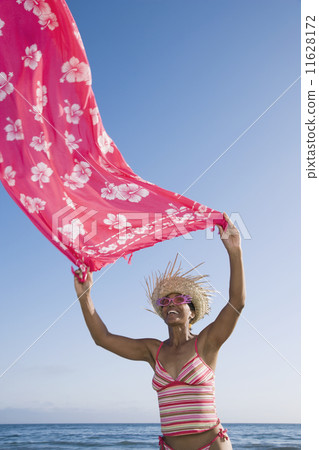 Mixed Race woman holding sarong in wind 11628172