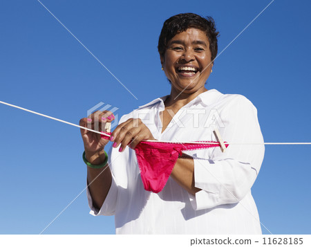 Mixed Race woman hanging underwear on line 11628185