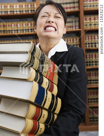 Asian woman carrying stack of library reference books 11628212