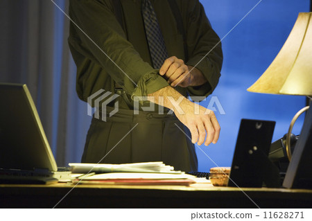 Hispanic businessman rolling up sleeve 11628271