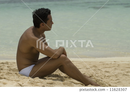 Hispanic man sitting on beach Hispanic man sitting on beach 11628307