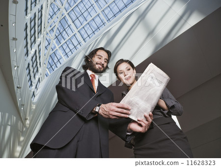 Hispanic businesspeople looking at newspaper Hispanic businesspeople looking at newspaper 11628323
