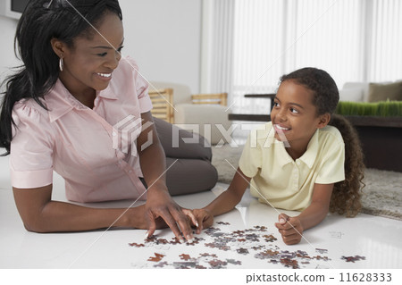 African American mother and daughter playing with puzzle 11628333