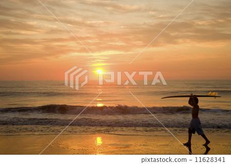 Asian boy carrying surfboard at beach 11628341