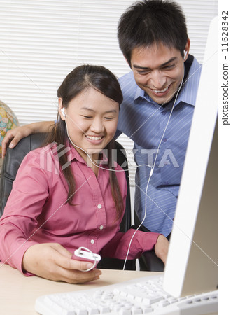 Two young businesspeople listening to mp3 player Two young businesspeople listening to mp3 player 11628342
