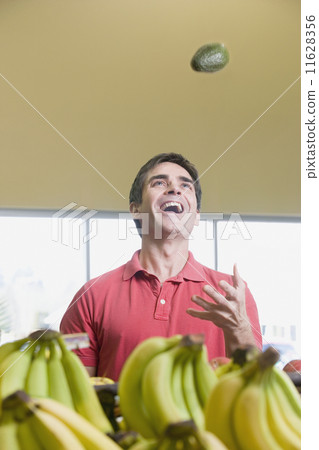 Man juggling avocados at grocery store Man juggling avocados at grocery store 11628356