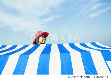 Hispanic woman standing behind beach sun shade 11628361