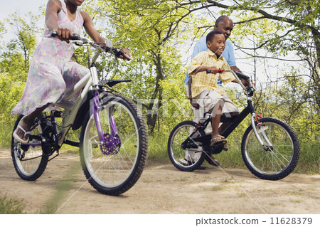 African grandfather teaching grandson to ride a bicycle in park 11628379
