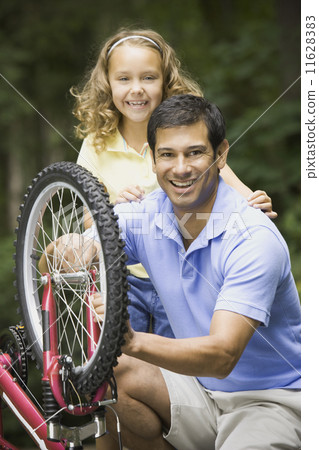 Hispanic father fixing daughter's bicycle Hispanic father fixing daughter's bicycle 11628383